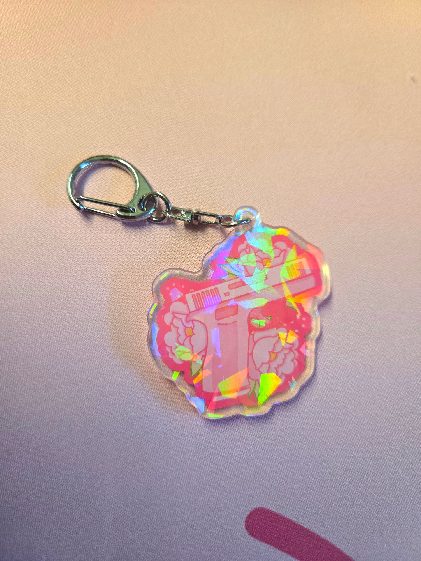 Holographic keychain with a gun design on a light pink background
